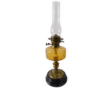 A Victorian oil lamp, with amber tinted glass reservoir, brass base and black glazed ceramic plinth, 60cm high to top of chim