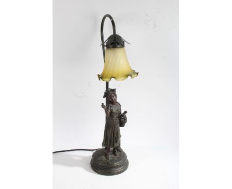 Art Nouveau style bronzed figural table lamp, in the form of a girl holding a basket of flowers, with frilled glass shade, 56