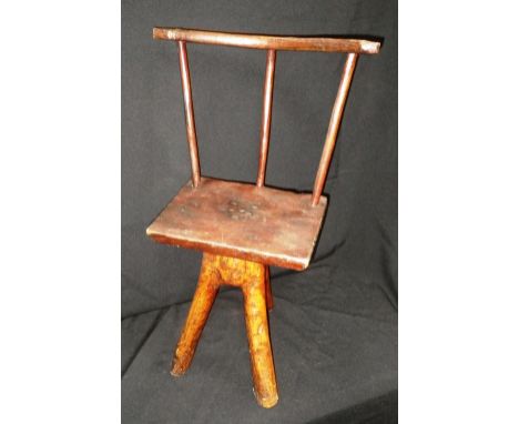 A NAIVE CHILD'S STICK-BACK CHAIR, sitting on three 'branch' legs