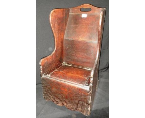 A GEORGE III OAK WING-BACK CHILD'S ROCKING CHAIR, with lift-up seat fitted a commode, 27.5" high