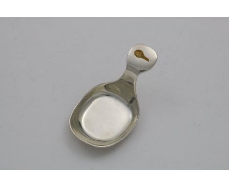 A CONTEMPORARY PARCELGILT CADDY SPOON with an incuse eagle's wing on the terminal and a textured underside "No.1" of a limite