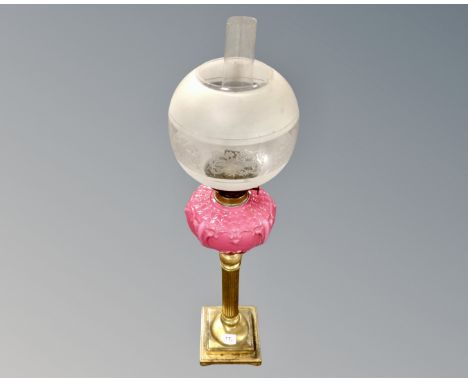 A brass oil lamp with opaque pink glass reservoir and etched glass shade  CONDITION REPORT: Reservoir heavily restored. 
