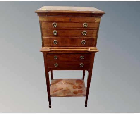 An Edwardian oak five drawer chest with under shelf on raised legs 