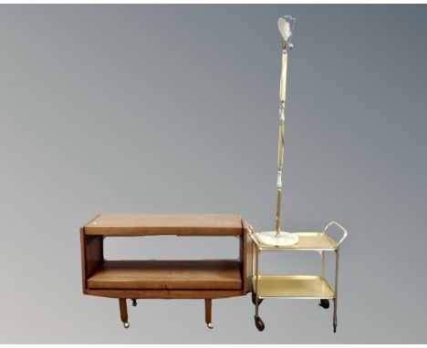 A 20th century two tier dumbwaiter trolley in a teak finish together with a further gilt two tier trolley and a standard lamp