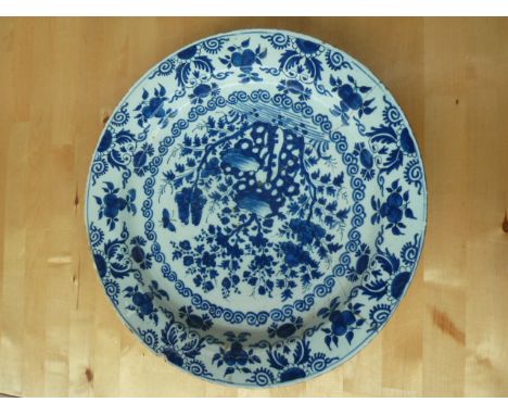 An 18th century Delftware blue and white charger, hand painted with blue glaze floral sprays and insects over a cream ground,