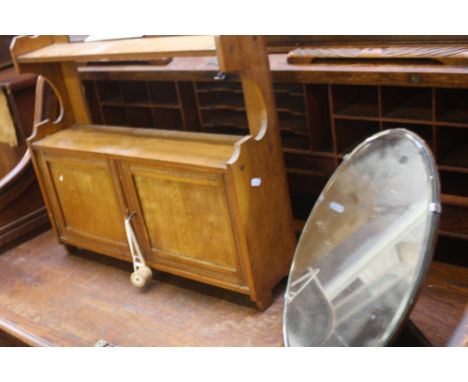 An early 20th pine hanging shelf, with 2 cupboard doors, 60cm wide, with an oval table mirror