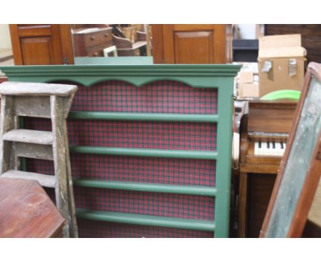 A set of green painted dresser shelves with tartan backing, 128cm wide, with a hanging wall mirror, 134cm high, with a set of
