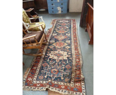 A decorative caucasian runner rug with multiple boarders and 8 central lozinges, 350cm x 126cm, with a large floral carpet
