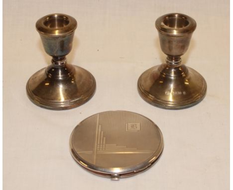 A silver circular compact with engine turned decoration, Birmingham marks and a pair of small silver squat-shaped candlestick