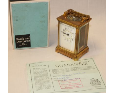 A French carriage clock with floral decorated enamelled dial in brass traditional case and retailers box by Boodle and Duntho