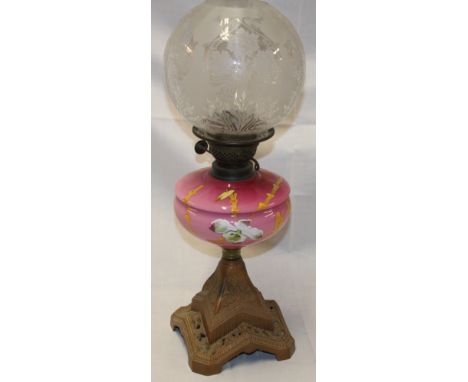 A Victorian oil lamp with cast iron base, floral ceramic reservoir and etched glass shade 