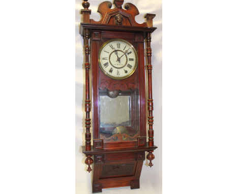 A Cornish wall clock by Wearne of Falmouth with painted circular dial in carved walnut rectangular glazed case with column su