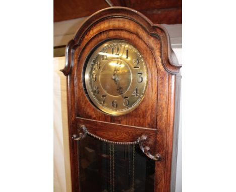 A 1920's/30's grandfather clock with brass circular dial in oak glazed arched traditional case