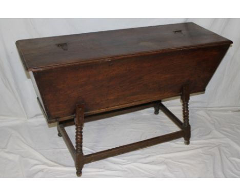 An early Continental elm dough kneading trough with hinged lid on turned legs joined by stretchers, 30" high x 48" long 