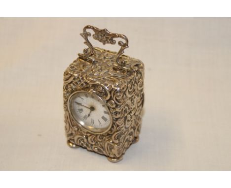 A good quality silver cased travelling clock with circular enamelled dial in a rectangular traditional case with raised scrol