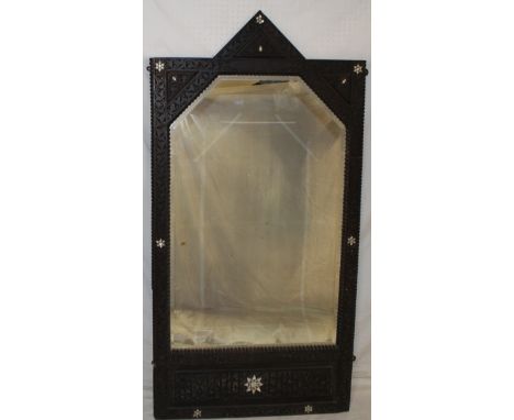 An Indian bevelled shaped rectangular wall mirror in carved teak frame with inset mother of pearl and bone emblems 59" high x