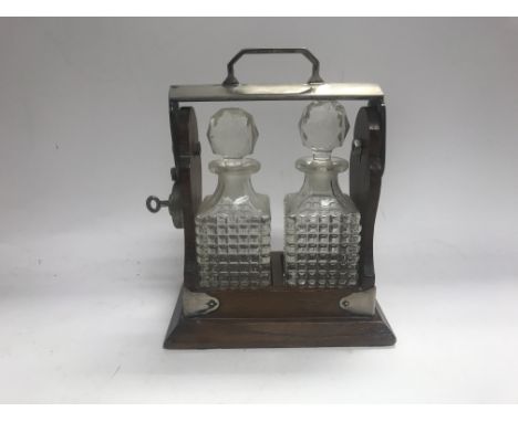 Two small tantalus decanters bottles with in a lockable cradle.