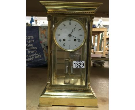 A French four glass brass mantle clock with visible mercury pendulum, the circular dial having Roman Numerals