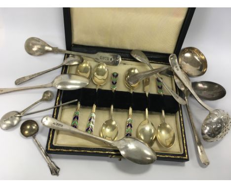 A cased set of enamel spoons together with a silver tea caddy spoon and various other spoons
