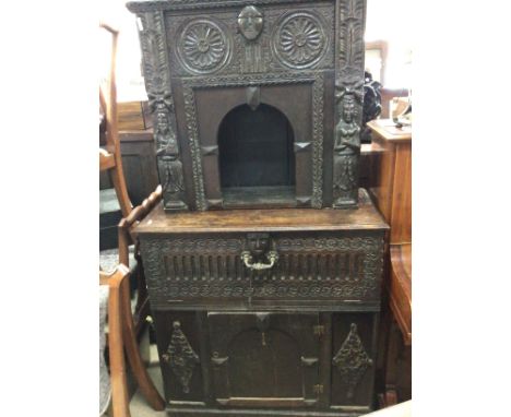 An 18th Century carved oak two section cabinet cupboard the top section with an open arch above a fall front above a cupboard