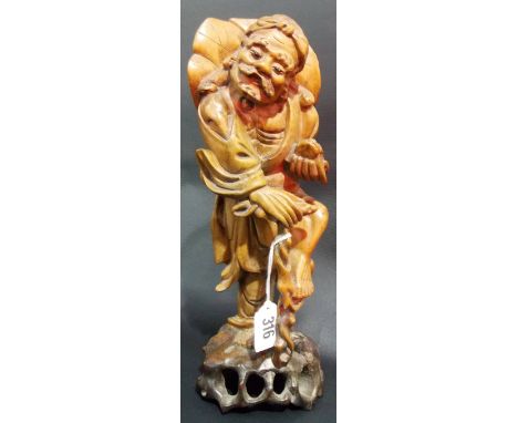 Chinese root carved figure of a sage holding a bat, his left foot raised on his walking stick, height 12'.