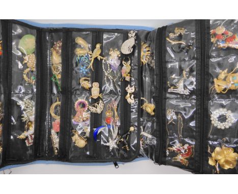 A large collection of vintage brooches to include owls, cats, and retro items all in a blue brooch display pouch Condition Re