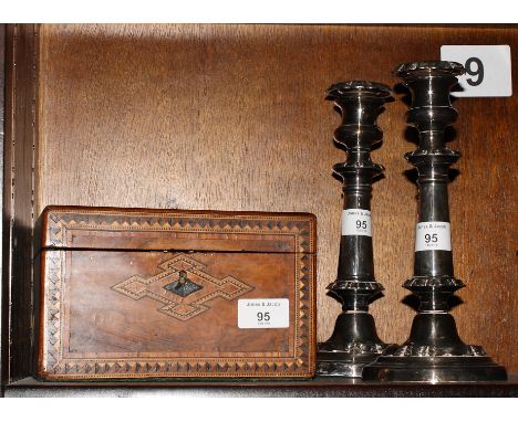 A burr walnut two-compartment tea caddy with geometric inlay and a pair of plated candlesticks