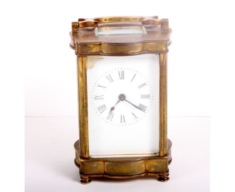 A carriage clock in gilt brass case with serpentine sides and plain white enamel dial, 5" high