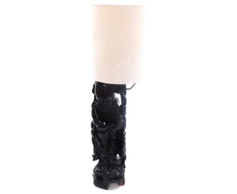 A Chinese hardwood table lamp modelled as Shoulao, carved in standing pose, holding a peach, with shade, 72cm high.