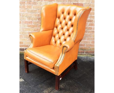 A TAN LEATHER BUTTON UPHOLSTERED WING ARMCHAIR  with scroll arms, on square moulded supports, 78cm wide across arms Condition