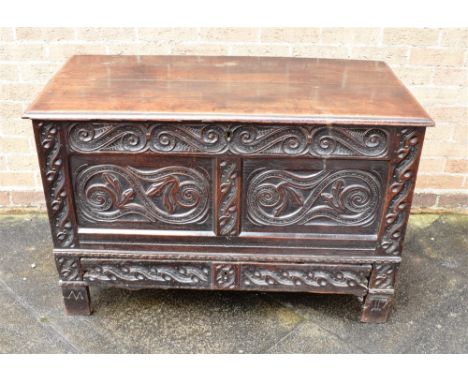 AN OAK MULE CHEST  the two panel front with carved decoration, initials 'M' and 'T' to the stile feet, 113cm wide 59cm deep 7