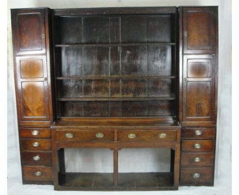 A Welsh Dresser:
18th century,the oak three tier panel, back shelf flanked by panel doors above four graduated drawers either