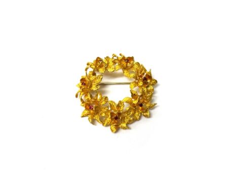 An 18ct gold and ruby set brooch, designed as a wreath of seven flowerheads, each centred by a circular cut ruby, gross weigh