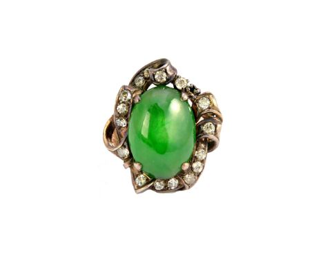 A gold, jade and diamond set ring, mounted with the oval jade cabochon at the centre, within a shaped surround, set with cush