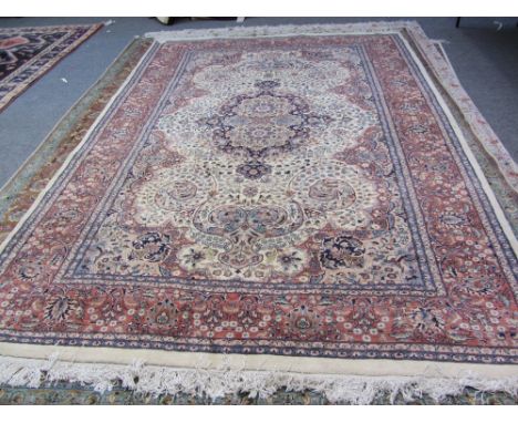 An Indian carpet, the ivory field with a fawn and indigo medallion, matching spandrels, all with intricate floral sprays, a b