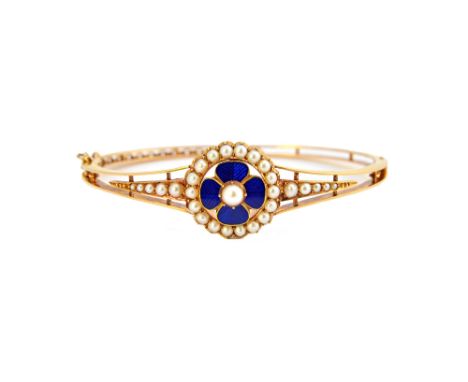 A gold, seed pearl set and blue enamelled oval hinged bangle, the front with a central blue enamelled flowerhead, in a border