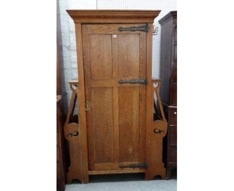 An Art Nouveau oak hall cupboard with panel door flanked by pair of stick stands, 121cm wide x 195cm high. 