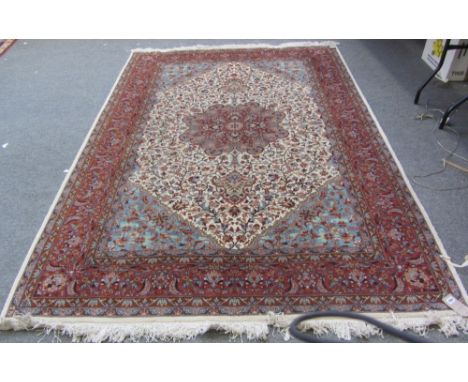 An Indian carpet, the ivory field with a madder rosette medallion, pale indigo spandrels, all with floral sprays, a complemen