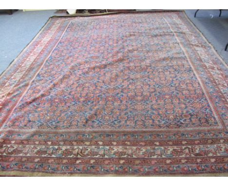 A Fereghan carpet, Persian, the indigo field with an allover madder herate design, an ivory waved vine and leaf border, 404cm