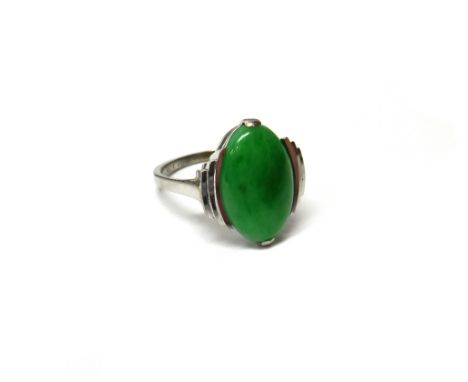 A white gold ring, mounted with an oval cabochon jade, between curved stepped shoulders, in an Art Deco design, detailed 18CT