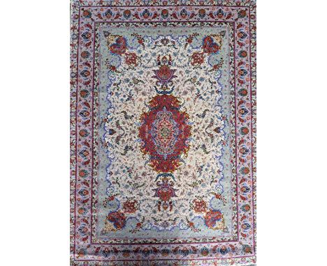 A part silk Kerman carpet, Persian, the cream field with a madder medallion, matching spandrels, outer surround, delicate flo