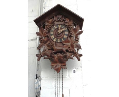 A Black Forest carved wooden cuckoo clock, early 20th century, with apex roof over a mechanised cuckoo aperture, the dial sur