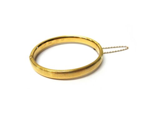 A gold oval hinged bangle, with reeded decoration, initial engraved and detailed 1910, on a snap clasp, detailed 15 CT, with 
