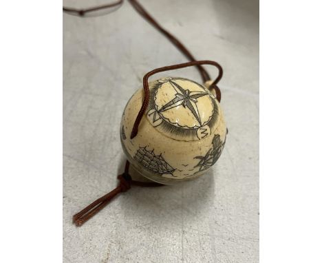 A BONE CARVED COMPASS ON A CORD 