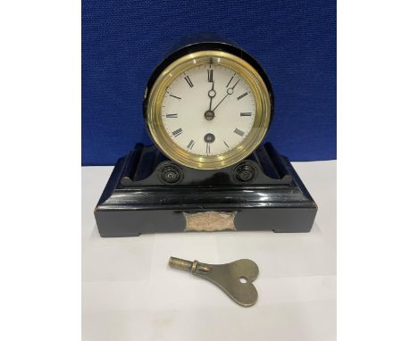 AN EBONISED CASED MANTLE CLOCK WITH 8 CM DIAL. HEIGHT 18CM AND KEY 