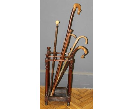 An Edwardian mahogany six division stick stand, with drip tray and five walking canes