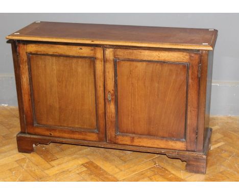 An early 19th century mahogany low cupboard, the rectangular top over a pair of panelled doors enclosing single shelf on brac