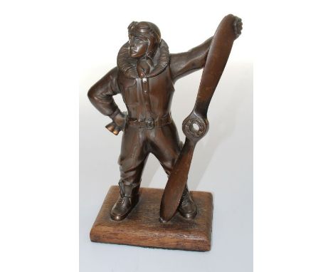 An Art Deco brown patinated bronze table lighter fashioned as an Airman in full flying attire, standing beside a propeller, o