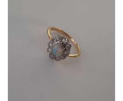 An 18ct and platinum early 20th century opal and diamond cluster ring. Opal cabochon in excellent condition with no crazing, 