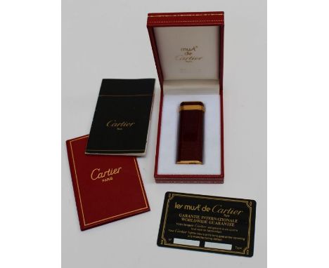 A Must de Cartier red mottled enamel and gold plated cigarette lighter in a Cartier box, with papers and card